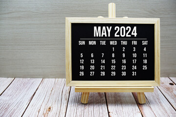 May 2024 monthly calendar on easel stand on wooden background