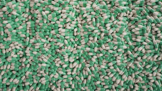 A mass of green-white SSRI antidepressant capsules rolling across the table.