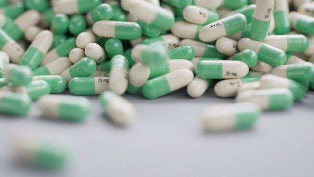 An avalanche of green-white antidepressant capsules rolling on the table.