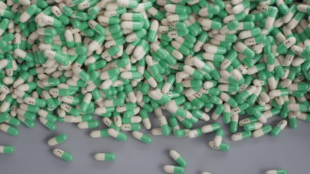 An avalanche of green-white antidepressant capsules rolling on the table.