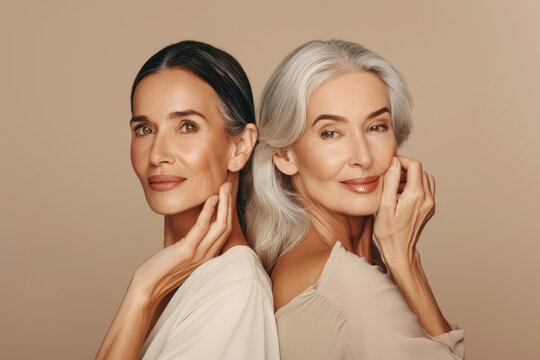 A photo of two beautiful women, one young and the other middleaged with silver hair, both posing back to back for an advertising campaign for skin care products