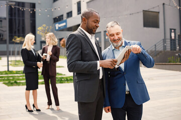Black businessman standing and talk with caucasian man in front of modern office