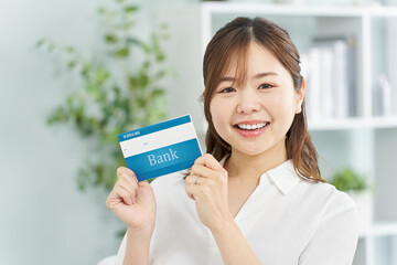 笑顔で銀行の通帳を持つ女性
