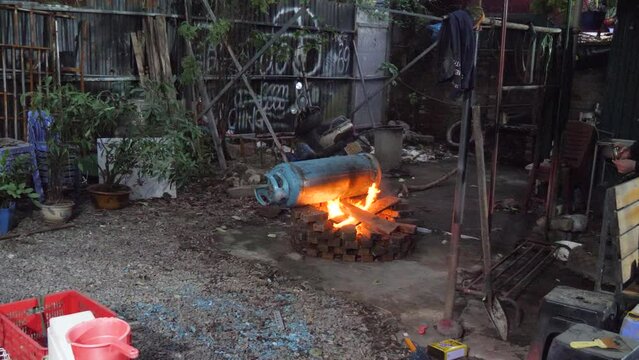 Old blue gas cylinder rolling away from danger of burning hot fire