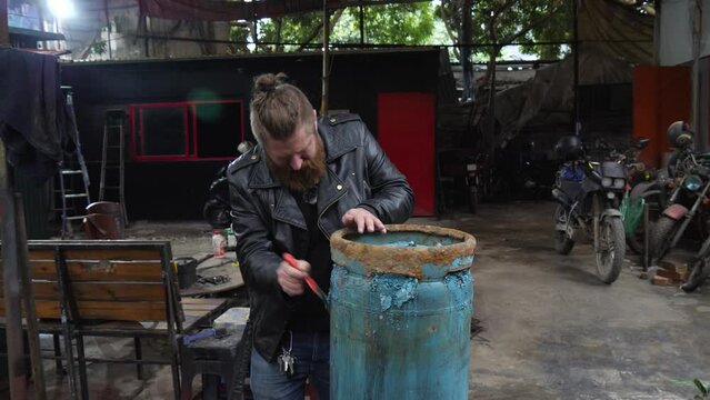 Rust flakes scrapped away, man working on gas tank conversion task