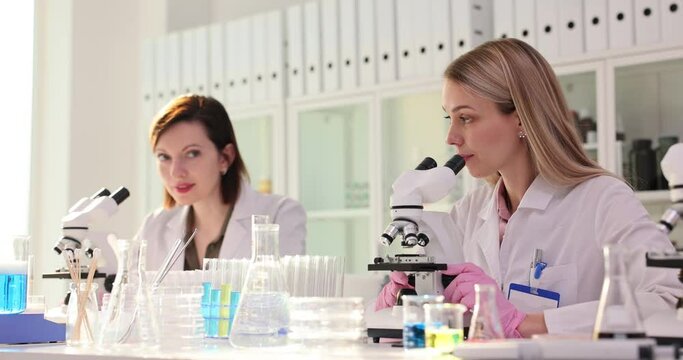 Female scientists see reaction in microscopes and give high five