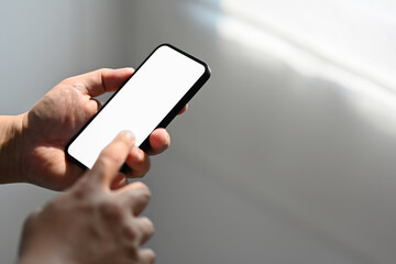 Man's hand using cellphone , reading an informations or email on the phone, Blurred background. Phone white screen mockup.