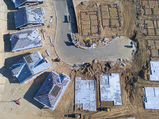 New construction of single family homes being built along a cul-de-sac is shown from an overhead, aerial view during the day.