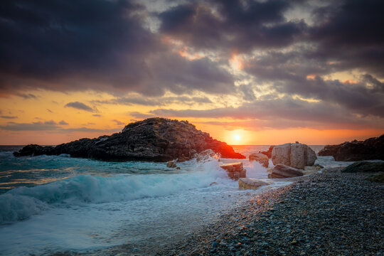 Seascape. Sea Ocean Sunrise time at the sea. Wave hit the rock at beach, sea water splash up to the sky with sun. Sunset Sundown at Sea. Storm.