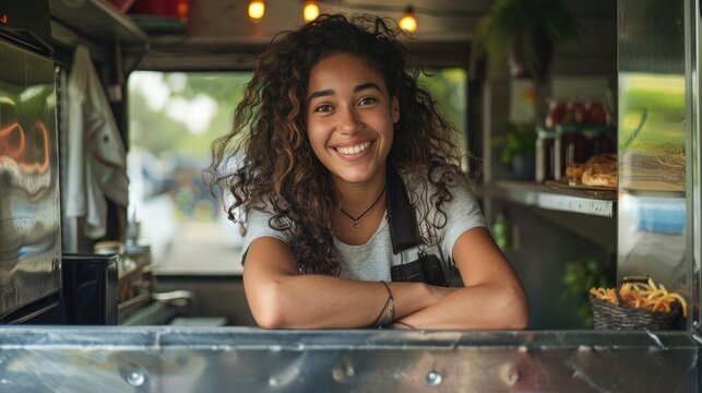 Portrait of happy female owner standing in food truck. Street food concept.