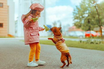 Little Girl Playing with a Dog in the Park Having Fun. Joyful kid and her puppy wearing trendy...