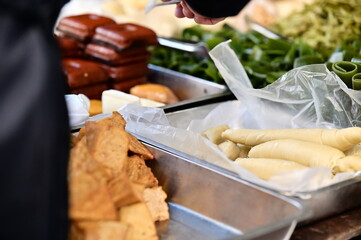 A close-up shot at a market stall features steamed bean curd rolls, a vegetarian alternative made...