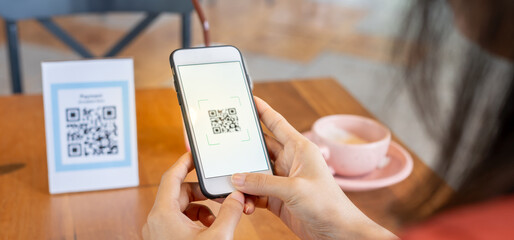 Woman use smartphone to scan QR code to pay in cafe restaurant with a digital payment without cash....