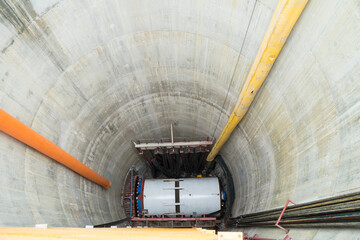 The drill head of tunnel boring machine into the construction shaft using a crane. Engineer and...