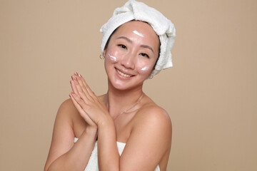 Portrait of cheerful Chinese young woman applying brightening lotion after evening shower