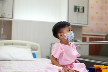 A 2-year-old child wearing a hospital gown was sick and was being treated in a hospital bed with...