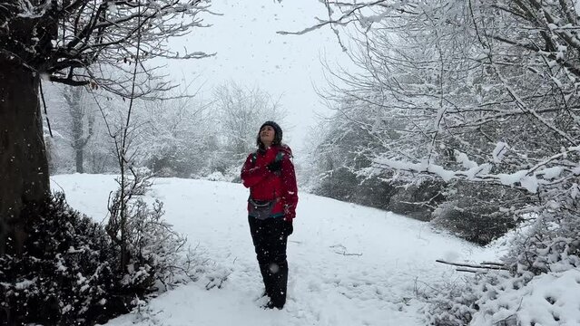 a woman looking at sky in heavy snowfall winter season in forest nature landscape wonderful scenic wide view of epic snow freezing cold day in Iran parrotia persica in snow hills trees in background