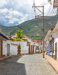 Colonial architecture on a cobblestone street in Santa Fe de Antioquia, Colombia, with lush green mountains in the backdrop