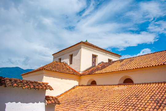 Colonial architecture in Santa Fe de Antioquia, Colombia with terracotta roof tiles against a vibrant blue sky