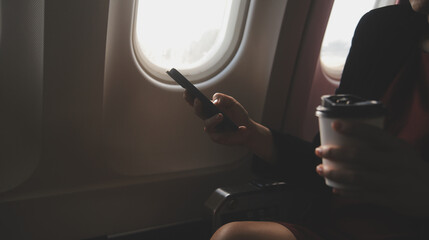 Blonde female tourist checking incoming notification on smartphone sitting on seat of airplane with...