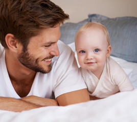 Happy, sweet and baby with father on bed relaxing, playing and bonding together at home. Smile, love and young dad laying with girl child, infant or kid in bedroom or nursery at family house.