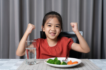 Kid shows strength of eats vegetables and nutritious food.
