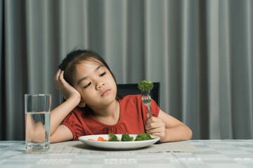 Little cute kid girl refusing to eat healthy vegetables. Children do not like to eat vegetables.