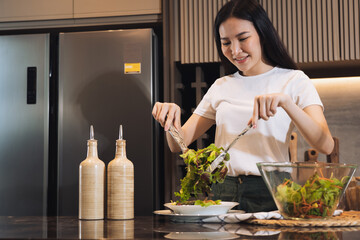 Asian housewife preparing fresh vegetables to make salad at home kitchen counter.