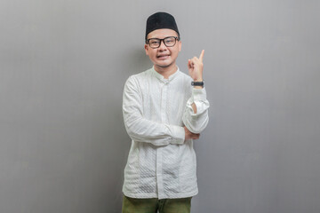 Asian Muslim man standing looking camera and pointing finger to empty space