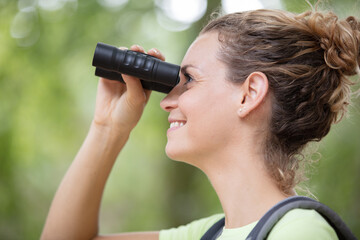 happy young woman hiking using binoculars