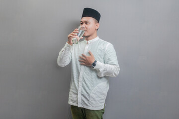 Happy asian muslim man drinking a fresh glass of pure water
