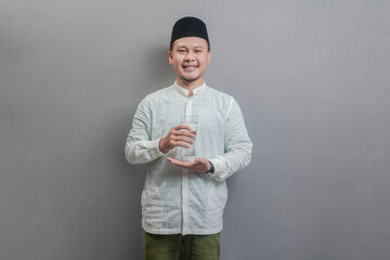 Happy asian muslim man holding glass of pure water give to camera
