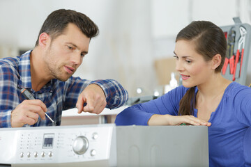 man and woman checkin a broken washing machine
