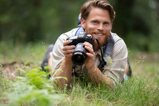 smiling photographer laying on the grass with camera