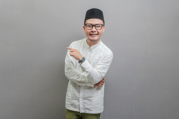Asian Muslim man standing looking camera and pointing finger to right empty space