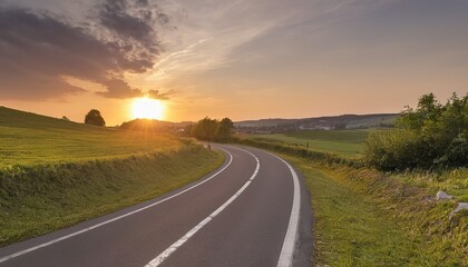 Fototapeta na wymiar A sunset shines upon a winding asphalt road in Molsheim
