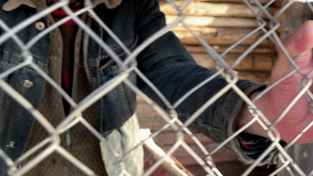 Male hand holding on to the barbed wire. Concept of not freedom as exclusion and desire for freedom. Man behind bars. Refugee in cage, human trafficking. Hands in jail. Imprisoned man. People abuse.