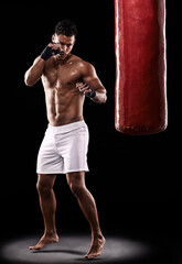 Fototapeta na wymiar Fitness, punching bag and man boxer in studio for body, training or performance on black background. Fighter, impact and topless male athlete with martial arts, mama or kickboxing match practice