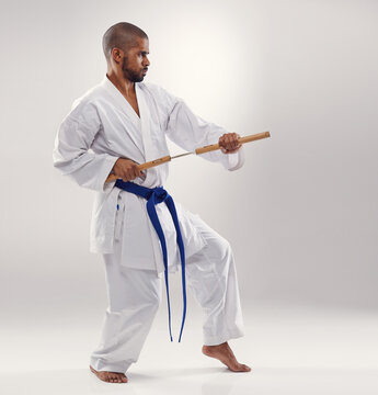 Karate, fight and man with nunchucks in martial arts, studio or training with weapon for defence on white background. Nunchaku, exercise and fighting with equipment in sport with skill and power