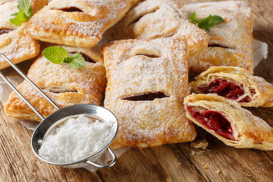 Sweet berry puff pastry with powdered sugar and mint close-up on the table. Horizontal