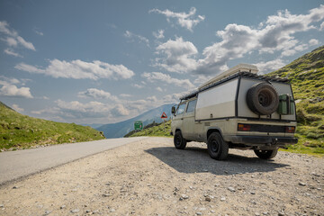 Old vintage expedition camper parked on top of Solkpass in Austria. Beautiful view from the top of mountain pass, asphalt road and gravel parking