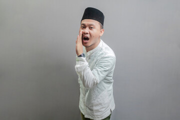 Happy asian muslim man hand on mouth whispering malicious talk conversation