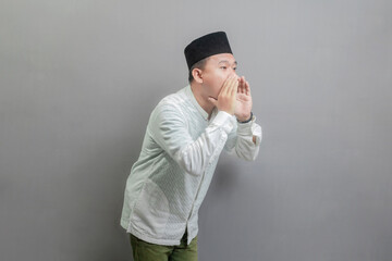 Asian Muslim man shouting and cupping hands around mouth