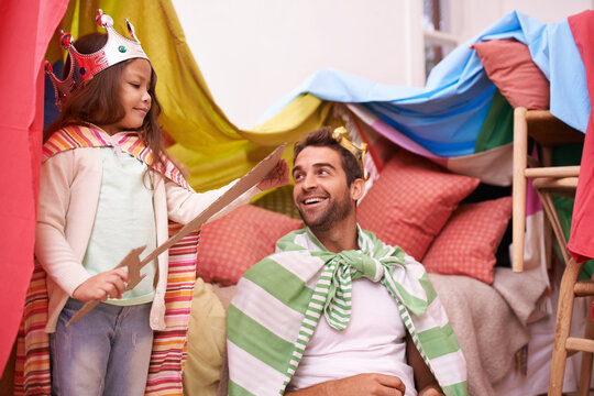 King, play or dad with princess in home in a bedroom fort with crown costume, girl or parent. Family castle, happiness or smile with a knight, father or an excited child in a dress up or sword game