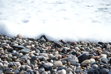 Closeup of wet pebbles in the wave foam