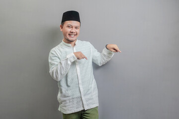 Happy asian muslim man recommend promo as pointing bottom, indicate down link