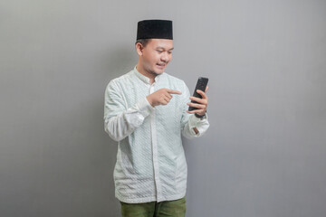 Portrait of an Asian Muslim man smiling pointing finger to his smartphone
