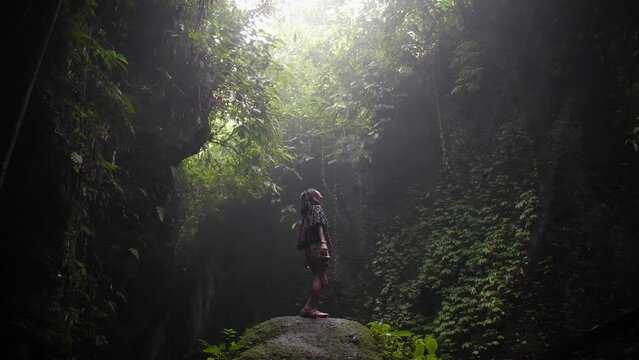 Woman in cave in the middle of the jungle. Bali, Indonesia. High quality FullHD slow motion footage.