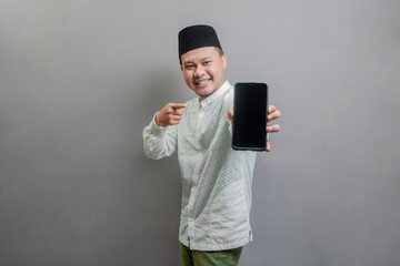 Portrait of an Asian Muslim man smiling with pointing finger to his smartphone
