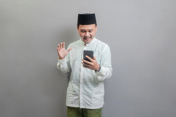 Asian Muslim man rasising hand and looking to his smartphone